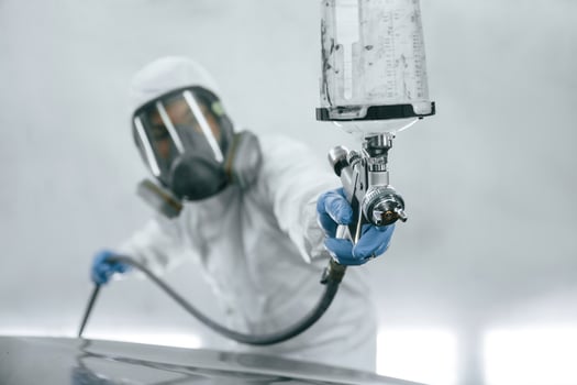 In protective mask and wear. Close ,,up, view of man that is painting a car by using spray guy photo