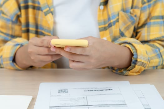 woman use phone scan barcode or QR codes to pay credit card bill after receiving document invoice. payment, receive, paying electricity, digital payments, technology, scanning. photo