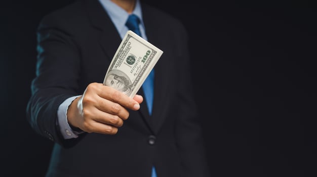 Close-up of a businessman holding US dollar bills while standing on a black background photo