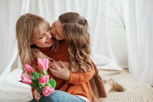 Embracing each ,,other. Celebrating mother's day. With flowers. Parent with daughter at home photo