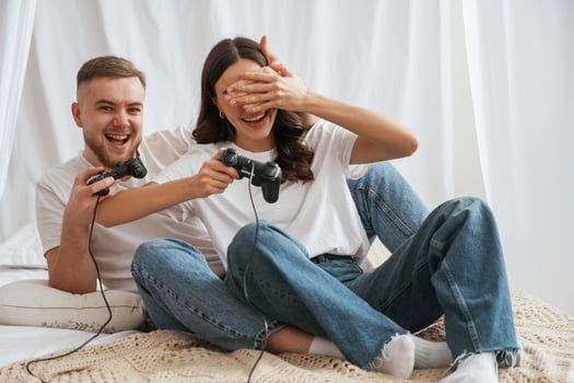 Holding joysticks, playing game. Young couple are together at home photo