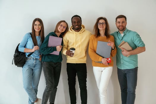 Holding notepads, and, coffee, cup. Group of young people are standing against white background photo