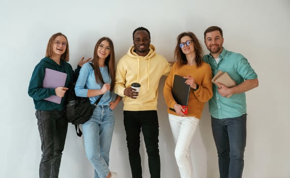Holding notepads and ,coffee,, cup. Group of young people are standing against white background photo