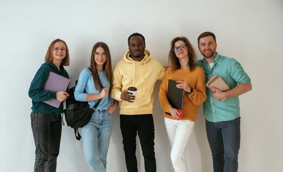 Holding ,notepads, and coffee cup. Group of young people are standing against white background photo