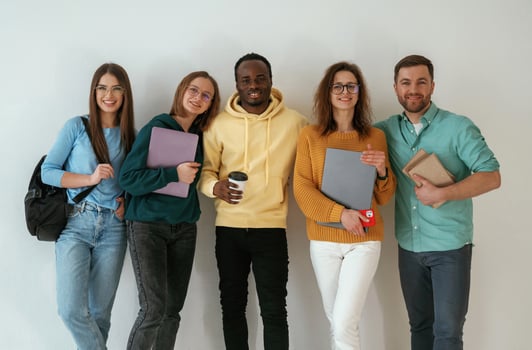 Holding notepads, and ,coffee cup. Group of young people are standing against white background photo