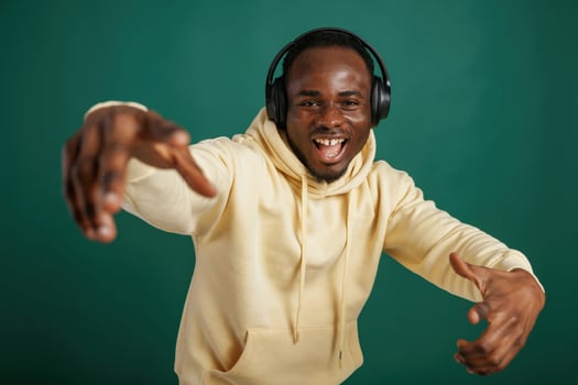 Listening to,, the music, dancing. African American man is standing against green background in the studio photo