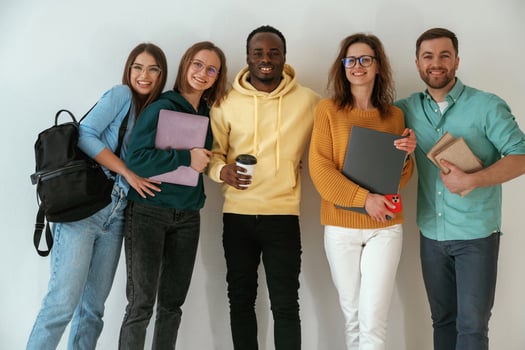 Holding notepads and, coffee cup. Group of young people are standing against white background photo