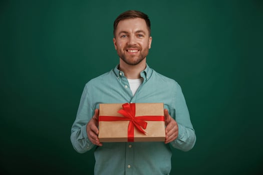 Little ,gift ,box in hands. Man is standing against background in the studio photo