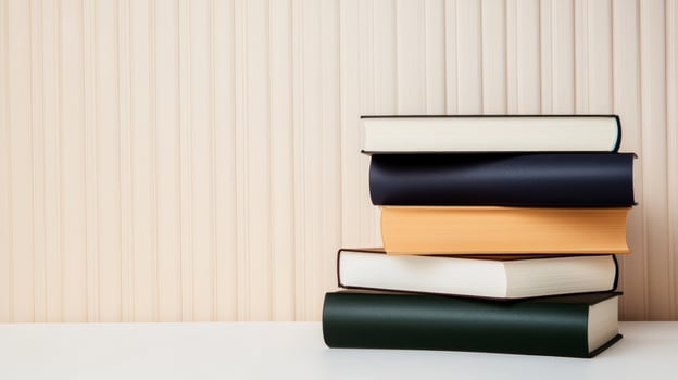 Stacked books in varying colors on a clean surface against a textured wall background showcasing a minimalist aesthetic photo