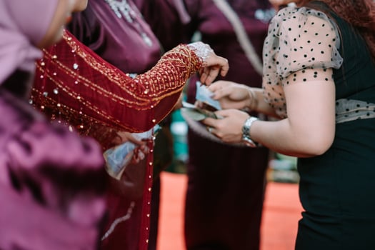 Monetary gift exchange at a cultural celebration featuring ornate clothing photo