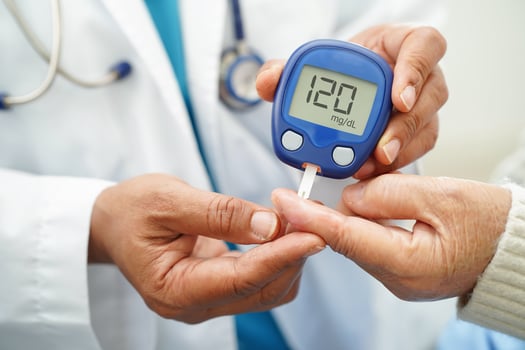 Asian doctor using digital glucose meter for check sample blood sugar level to treatment diab photo