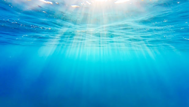 Sunlight beams penetrating the crystal-clear blue ocean, creating serene underwater atmosphere. Concept of nature backgrounds, ocean depth, marine beauty, travel, diving, and peaceful nature photo