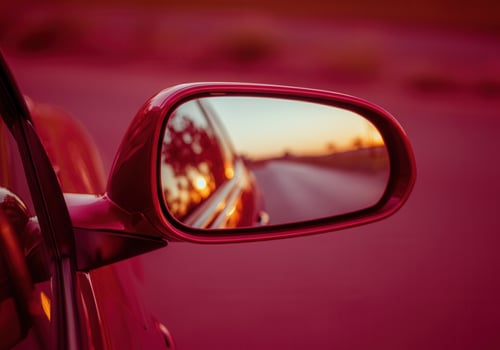 Sunset reflection in dark red cherry car side mirror on scenic road photo