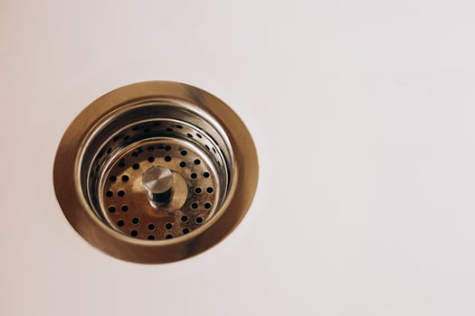 Drain with metal strainer on white surface in modern kitchen photo