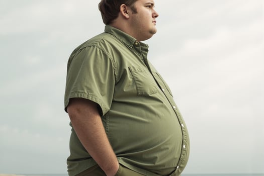 Overweight man standing on beach contemplating weight loss journey photo