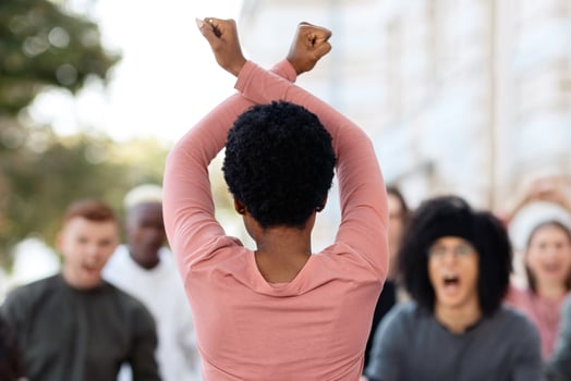 Rear view of african american female activist leading angry protestors multiracial group of mellannial men and women, demonstrators fighting against government politics, striking on the street photo