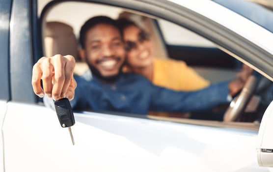 We bought car. Happy couple showing car key, sitting in new car, focus on hand photo