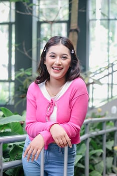 A radiant young woman with a charming smile and trendy pink cardigan is ready for adventure. Her happiness and anticipation add to the appeal of travel and the open road. photo