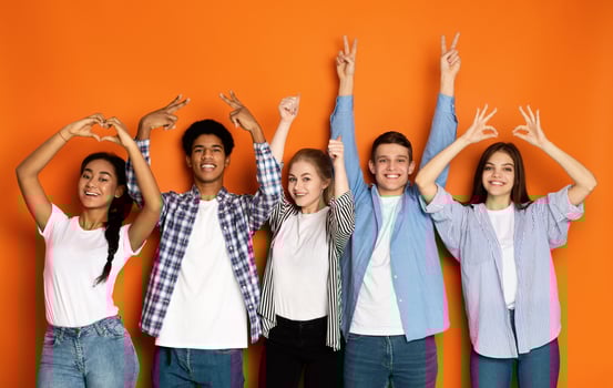 Young friends gesturing with hands over orange studio background, standing in row and smiling photo