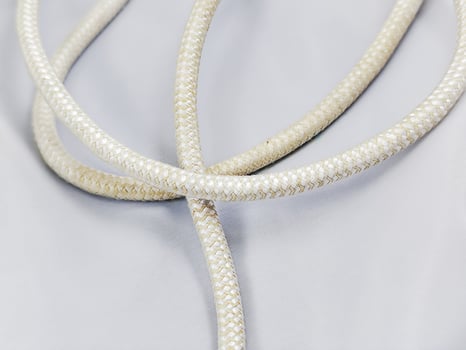 Detail Shot Fabric-Wrapped Cable on White Fabric Surface photo