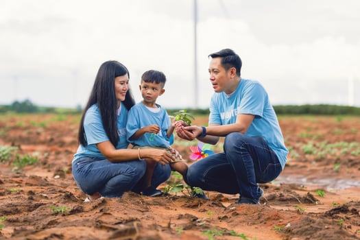 family of three, a man and two children, are planting a tree together photo