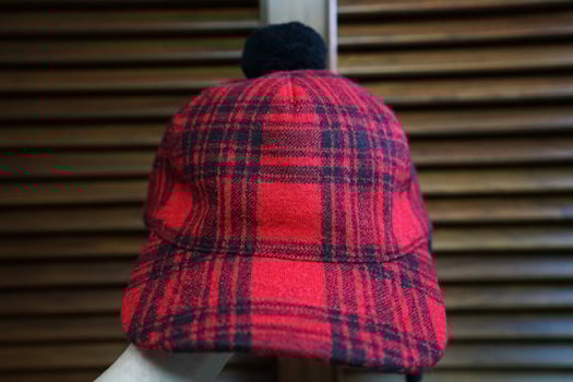 Close up 'GUCCI' logo tag and detail of red and black buffalo check winter hat photo