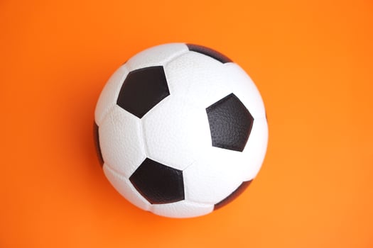 Football, soccer ball on orange background. Concept,sport equipment,symbol of energy, teamwork, and fitness. Ideal for promoting active lifestyle, workout, health, and football-related content. photo