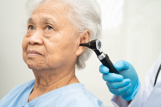 Otolaryngologist ENT physician doctor examining senior patient ear with otoscope, hearing loss problem. photo