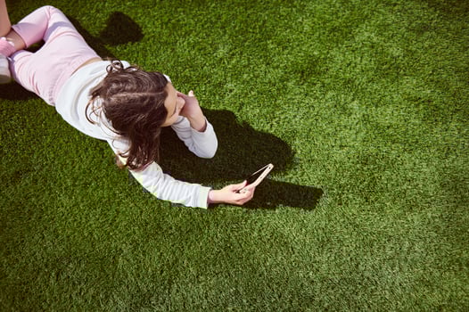Young Girl Relaxing on Grass Using a Phone on a Sunny Day photo