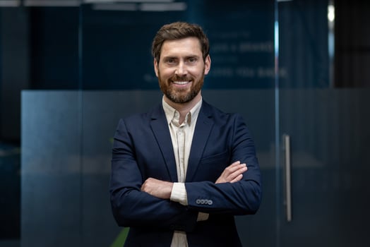 Portrait of a sleepy young businessman standing in the office, arms crossed on his chest, confidently and smilingly looking at the camera. photo