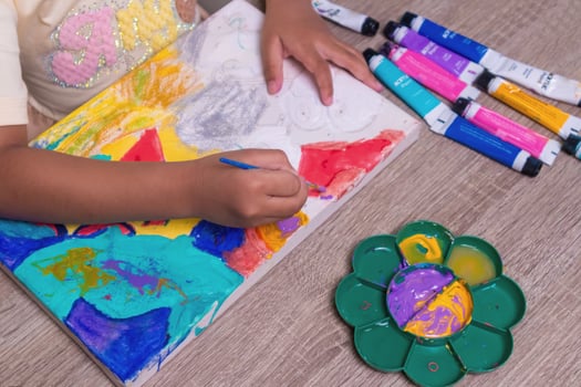 A little girl painting on canvas on the table photo