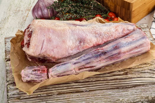 A raw pork leg on a wooden cutting board photo