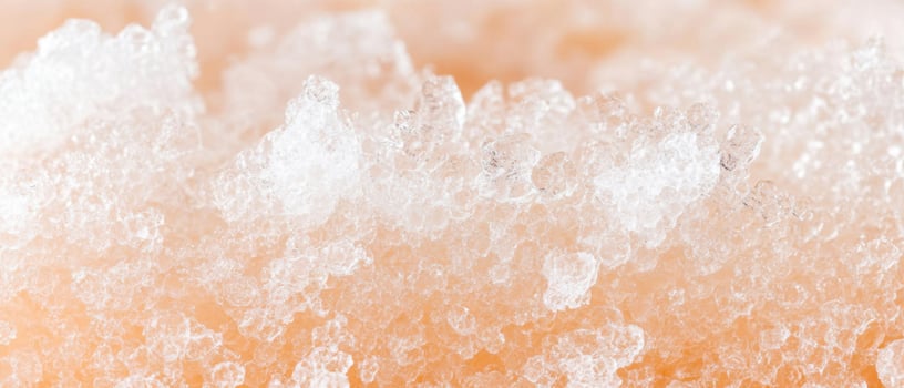Close up of crushed ice texture with light orange glow. Small jagged pieces reflect light. Abstract frozen background with cold crystals and frost photo