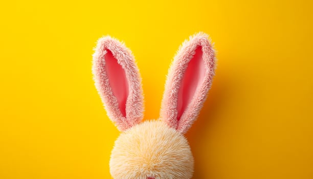 Bunny ears on bright backdrop. Soft pink bunny ears are positioned against a vibrant yellow background, creating a playful and cheerful atmosphere. photo