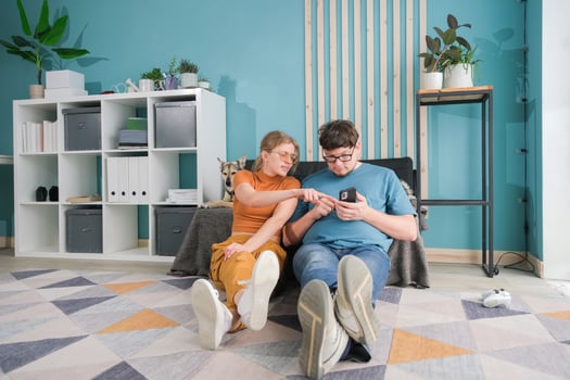 happy couple sitting on floor near dog in living room photo