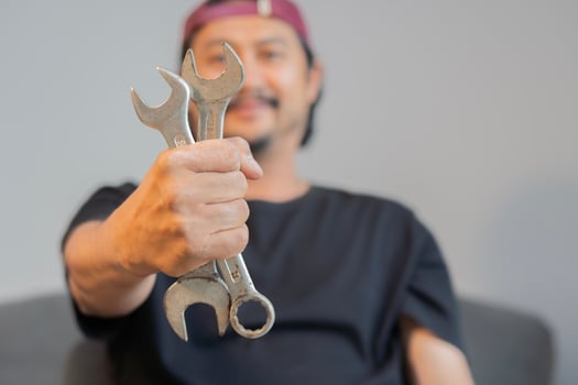 Smiling Asian adult man with wrenches on hands to repair his car at home. photo