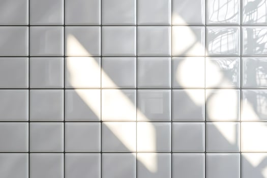 Sunlight creating shadows on white square tiles wall photo