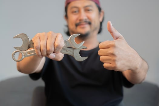 Cropped image of mechanics working in auto service. One is holding a wrench and showing Ok sign. photo