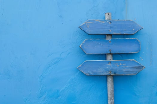 Three blank directional signs pointing in different directions on blue wall photo
