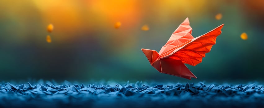 Colorful bird over blue paper. A vibrant orange origami bird soars over carefully folded blue paper, capturing a sense of freedom and creativity. photo