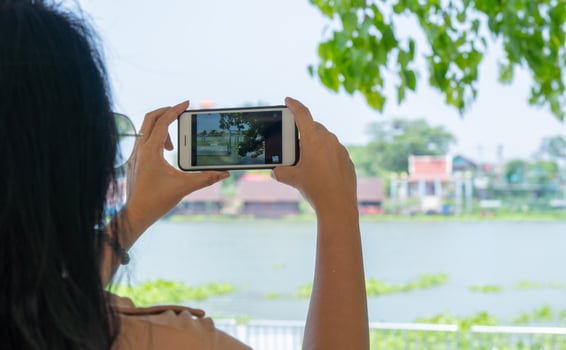 Asian woman takes pictures of Chao Phraya River, Thailand on a smartphone, a view from the back. photo