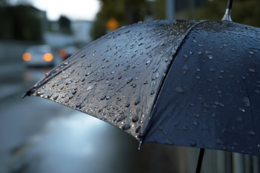 Black umbrella protecting from rain in a city street photo