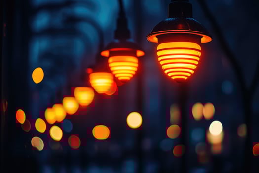 Row of illuminated orange lamps hanging in a city park at night photo