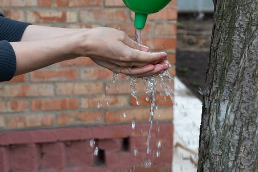 Washing hands after ground works in garden from garden tap photo