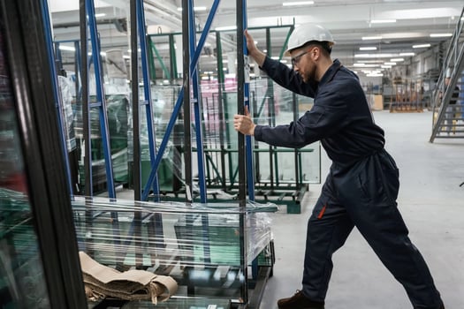 Moving the ,parts of windows. Factory worker is indoors with hard hat photo