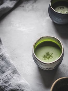 Cup of green tea sits on a table next to two other cups photo