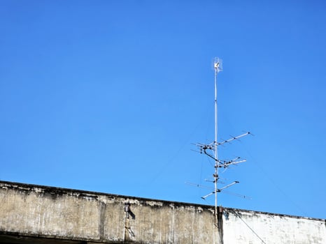 TV Antenna on the Roof of Old Building with Blue Sky. photo