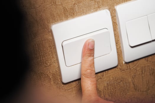 Person turning off the light switch in a home environment photo