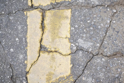 Cracked asphalt pavement with faded yellow line on the street photo