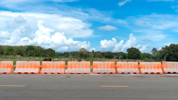 Aspahlt road with barrier guard lens. Background is a grassland and cows, which is an agricultural area and some forest. Under a blue sky. photo